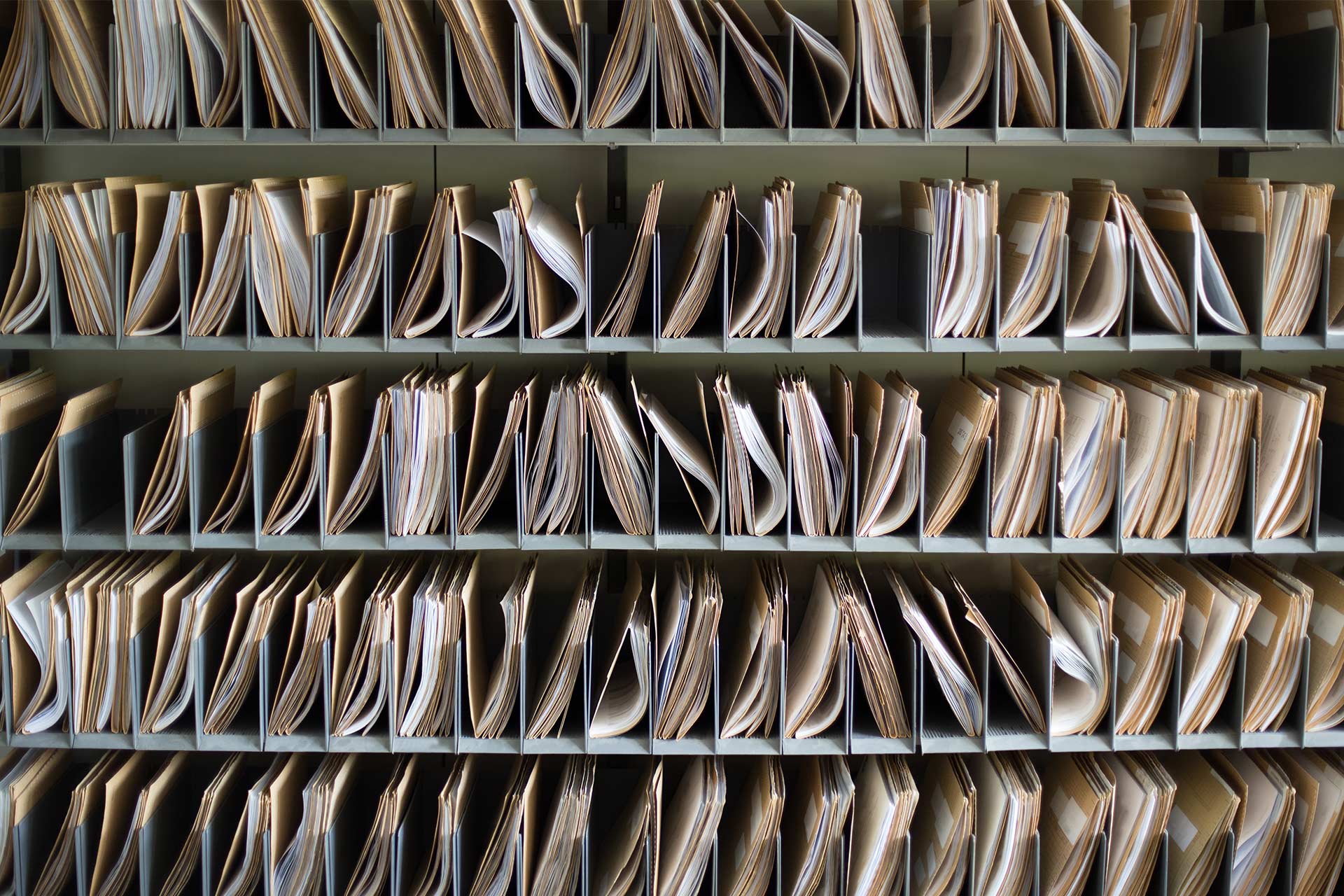 Fichiers papier stockés sous forme de dossiers, représentant le processus de sauvegarde de l’ordinateur comme une forme d’archivage