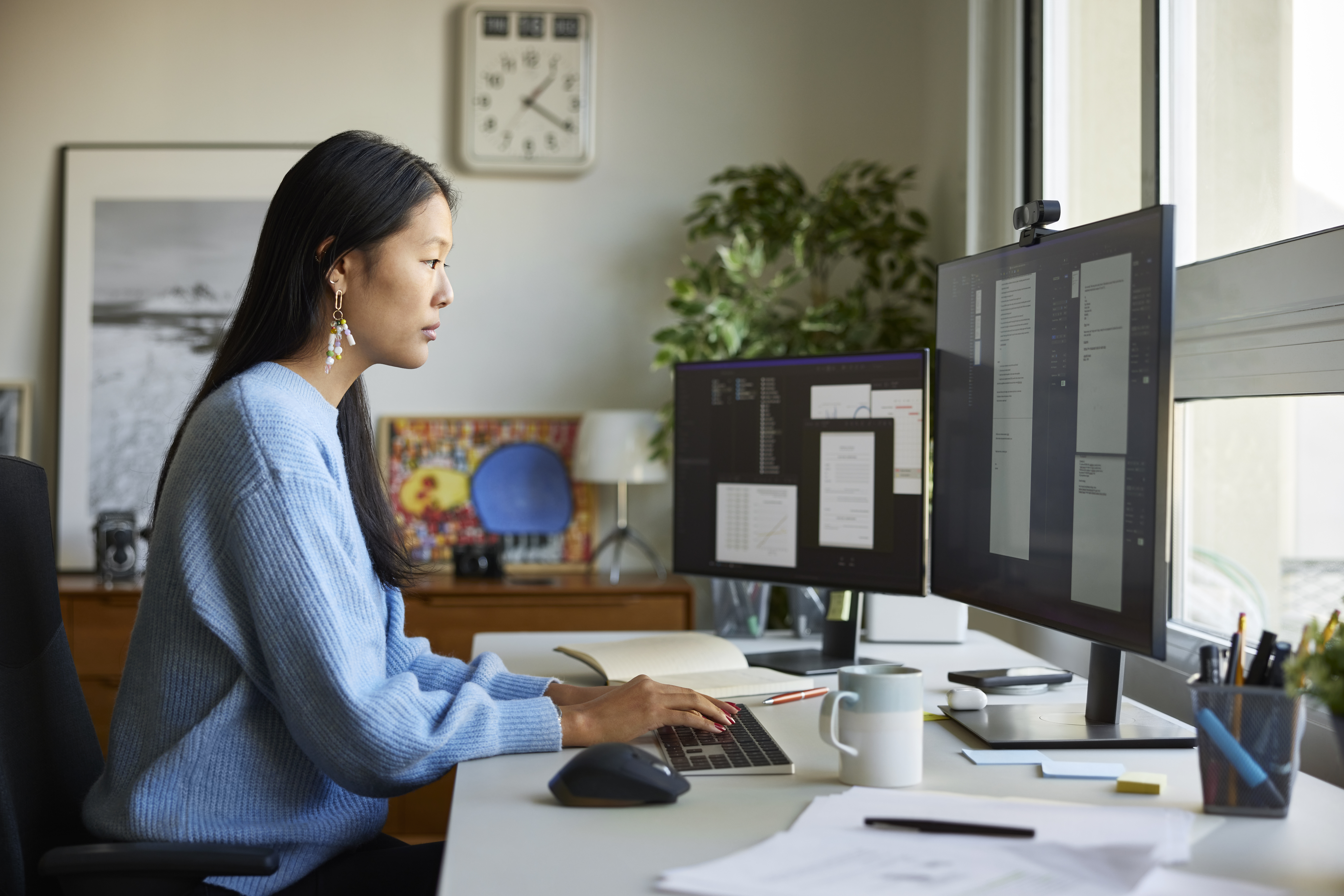 Een professional werkt op afstand aan verschillende documenten op twee computerschermen.